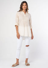 [Color: Natural] A woman wearing a bohemian off white long sleeve cotton tunic top with button front and embroidered detail. 