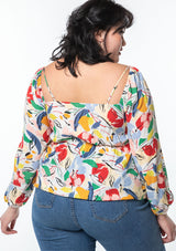 [Color: Natural/Brick Red] A model wearing a multi color floral print bohemian peplum top with a gathered front detail.