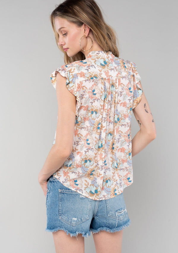 [Color: Natural/Coral] A back facing image of a blonde model wearing a classic bohemian popover top in a natural and coral floral print. With short flutter cap sleeves, a ruffled neckline with tassel ties, and a relaxed silhouette. 
