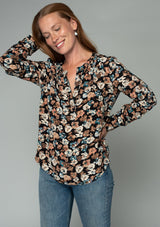 [Color: Black/Natural] A front facing image of a red headed model wearing a lightweight long sleeve top in a black and natural floral print. With a split v neckline and a relaxed flowy fit. 