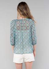 [Color: Cream/Navy] A back facing image of a blonde model wearing a sheer chiffon bohemian blouse in a blue floral geometric print. With three quarter length sleeves and a split neckline with ties. 
