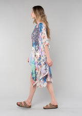 [Color: Natural/Coral] A side facing image of a blonde model wearing a lightweight bohemian kimono in a natural and coral mixed floral print. With half length kimono sleeves, an open front, and side slits. 