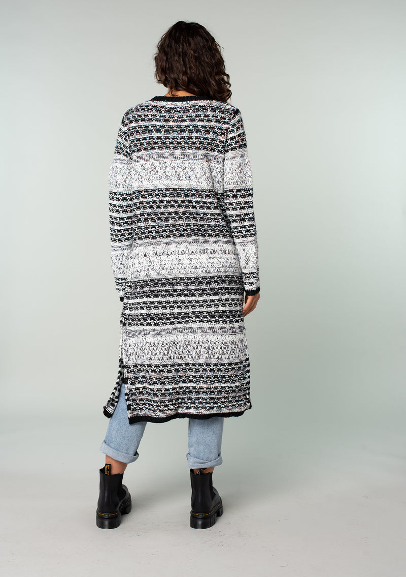 [Color: Black/Grey] A back facing image of a brunette model wearing a black and grey mixed knit long duster cardigan.