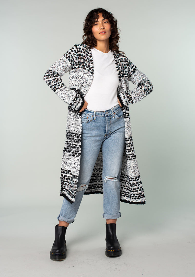 [Color: Black/Grey] A front facing image of a brunette model wearing a black and grey mixed knit long duster cardigan.