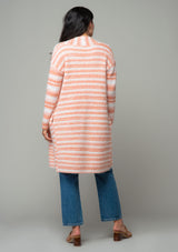 [Color: Ivory/Peach] A back facing image of a brunette model wearing a white and peach striped long cardigan. With an open front, contrast striped long sleeves, a shawl collar, and side pockets. 