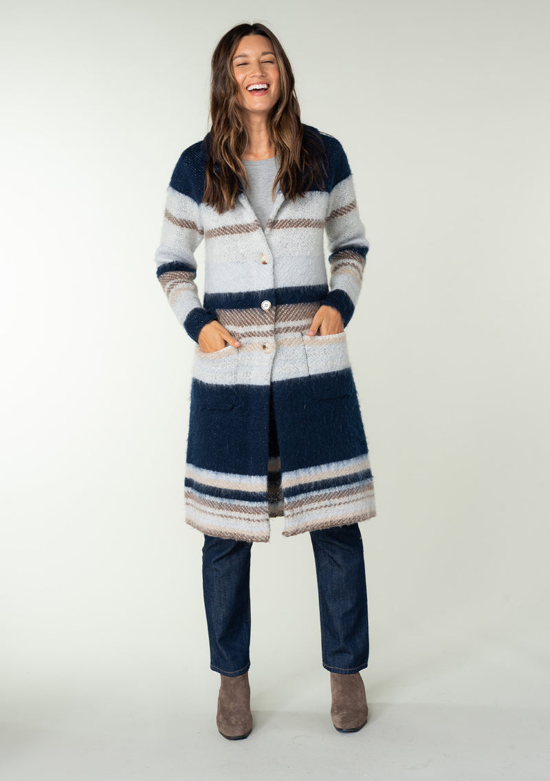 [Color: Ivory/Navy] A full body front facing image of a brunette model wearing a soft sweater coat in a blue and ivory stripe. With a button front, long sleeves, side patch pockets, and a notched lapel. 