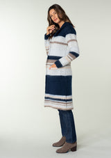 [Color: Ivory/Navy] A side facing image of a brunette model wearing a soft sweater coat in a blue and ivory stripe. With a button front, long sleeves, side patch pockets, and a notched lapel. 