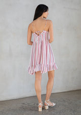 [Color: Natural/Pink] A model wearing a pink stripe sleeveless mini dress with a strappy back and flowy silhouette. 