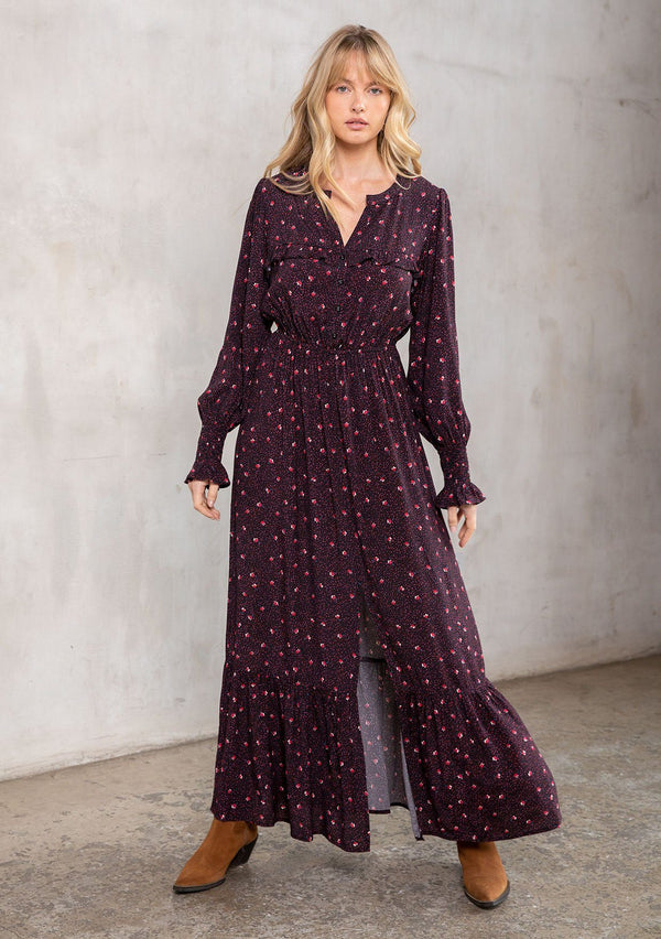 [Color: Black/Red] A model wearing a timeless bohemian black and red dot floral maxi dress. With long sleeves, a button front, and ruffled yoke detail. 