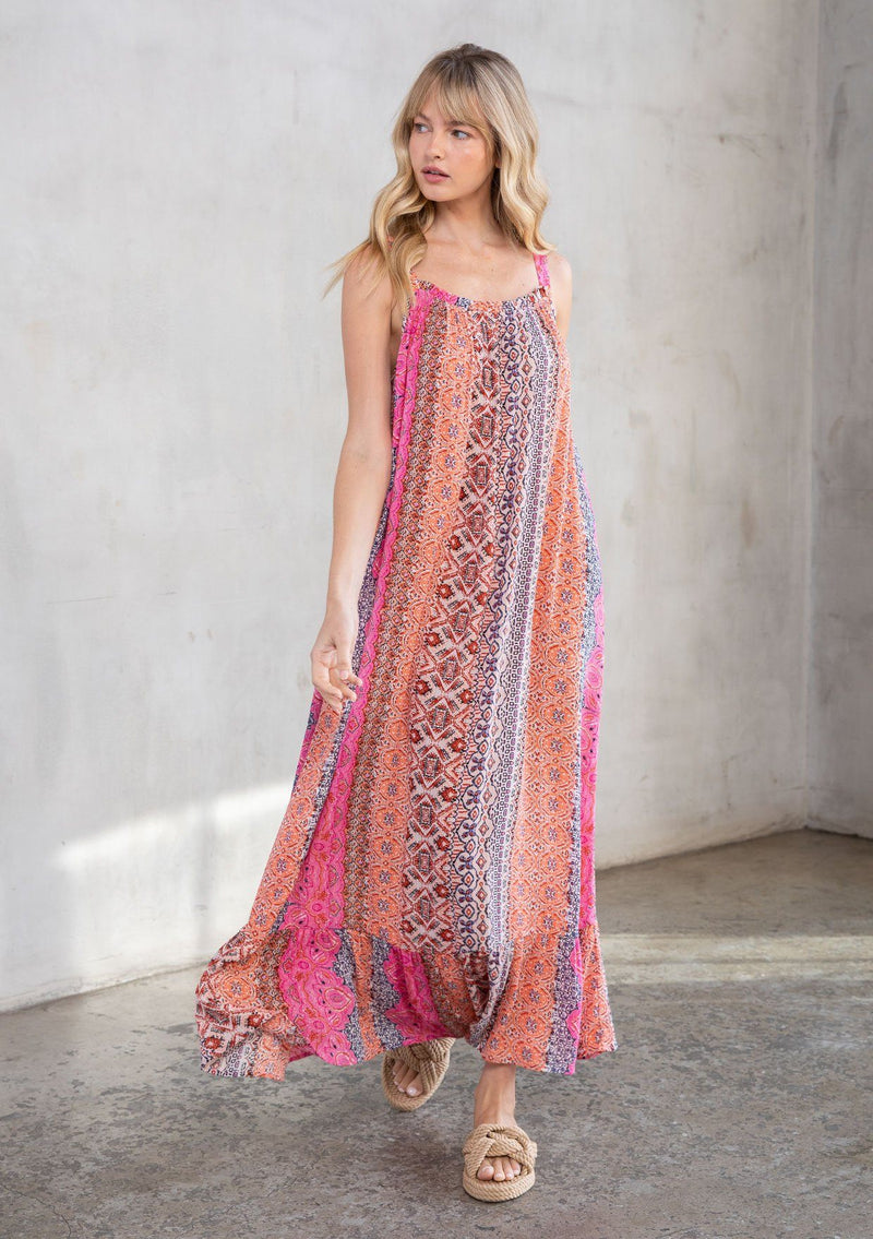 [Color: Coral Multi] A model wearing a vacation ready sleeveless maxi dress in a multicolor mixed print. With a ruffled round neckline, a relaxed flowy fit, and metallic thread details.