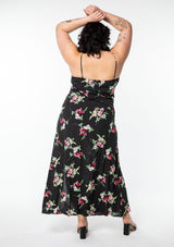 [Color: Black/Red] A model wearing a classic black bohemian maxi slip dress in a pink floral print. With adjustable spaghetti straps, a side slit, and lattice trim.
