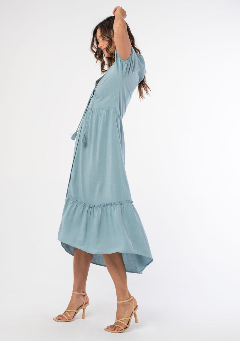 [Color: Dusty Teal] A model wearing a teal flowy bohemian mid length dress with a button front and short puff sleeves.