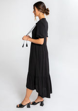 [Color: Black] A model wearing a black flowy bohemian mid length dress with a button front and short puff sleeves. 