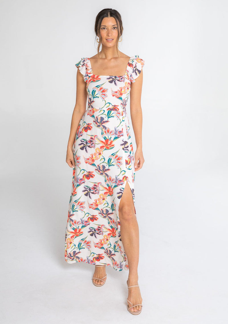 [Color: Ivory/Red] A model wearing a white bohemian maxi dress with pink and red tropical floral print. With a slim fit smocked bodice and a flowy skirt.