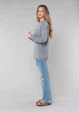 [Color: Heather Grey] A blonde model wearing a cozy heather grey knit hoodie sweater with long sleeves and a front kangaroo pocket. 