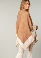 [Color: Heather Camel/Heather Ivory] A half body back facing image of a blonde model wearing a soft and warm mid length sweater cape. An open front cape cardigan with a contrast border design. Perfect fall sweater, great for layering. 