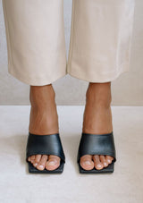 [Color: Black] Alohas classic black leather slip on mule dune sandal with a statement pyramid block heel. 