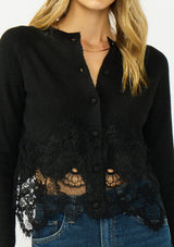 [Color: Black] A detail image of a blonde model wearing a black lace cardigan with a button front. 