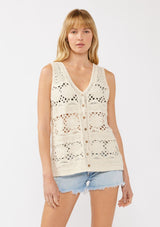 [Color: Natural] A front facing image of a blonde model wearing a button-front vest crafted in a cotton floral crochet pattern. Featuring a sleeveless design and flattering V-neckline, this breezy resort vest is perfect for beach days and vacation styling.