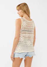 [Color: Natural] A back facing image of a blonde model wearing a button-front vest crafted in a cotton floral crochet pattern. Featuring a sleeveless design and flattering V-neckline, this breezy resort vest is perfect for beach days and vacation styling.