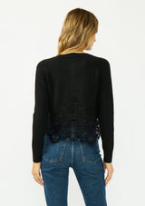 [Color: Black] A back facing image of a blonde model wearing a black lace cardigan with a button front. 