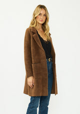 [Color: Brown/Black] A side facing image of a blonde model wearing a brown plaid sweater coat with a notched collar, button front, and front patch pockets. 