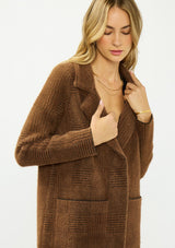 [Color: Brown/Black] A detail image of a blonde model wearing a brown plaid sweater coat with a notched collar, button front, and front patch pockets. 