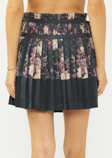 [Color: Grey/Dusty Rose] A back facing image of a grey floral pleated skirt with a satin hem, clipped lurex, paperbag waist, and side tie details. 