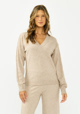 [Color: Heather Taupe] A front facing image of a brunette model wearing a beige v neck sweater with a cable knit detail and styled with a matching bottom. 
