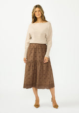 [Color: Heather Light Taupe] A front facing image of a brunette model wearing a light brown pullover sweater with a boat neckline and ribbed cuffs. Styled with a brown embroidered skirt. 