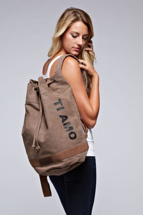 [Color: Khaki] A blonde model wearing a cotton blend khaki sack backpack with a drawstring closure. 