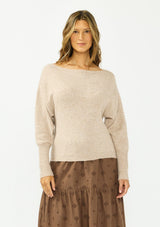 [Color: Heather Light Taupe] A front facing image of a brunette model wearing a light brown pullover sweater with a boat neckline and ribbed cuffs. Styled with a brown embroidered skirt. 