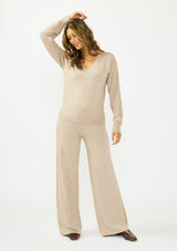 [Color: Heather Taupe] A front facing image of a brunette model wearing a beige v neck sweater with a cable knit detail and styled with a matching bottom. 