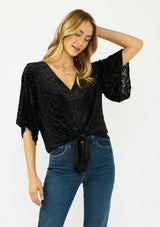 [Color: Black] A front facing image of a blonde model wearing a black floral burnout tie front top with flowy half length sleeves and a v neckline. 