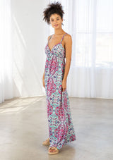 [Color: Coral/Mint] A side facing image of a brunette model wearing a pink and blue bohemian printed maxi dress with spaghetti straps, a v neckline, and an empire waist. 
