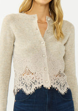 [Color: Heather Oat] A detail image of a blonde model wearing a beige lace cardigan with a button front. 