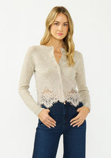 [Color: Heather Oat] A front facing image of a blonde model wearing a beige lace cardigan with a button front. 