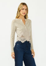 [Color: Heather Oat] A side facing image of a blonde model wearing a beige lace cardigan with a button front. 