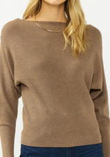 [Color: Mocha] A detail image of a blonde model wearing an brown pullover sweater with a boat neckline and long sleeves that taper at the cuffs. 