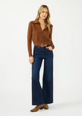 [Color: Brown] A front facing image of a blonde model wearing a brown cropped sweater with a wide collar, button front, and ribbed trim. Styled with a dark was denim. 