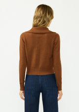 [Color: Brown] A back facing image of a blonde model wearing a brown cropped sweater with a wide collar, button front, and ribbed trim. Styled with a dark was denim. 