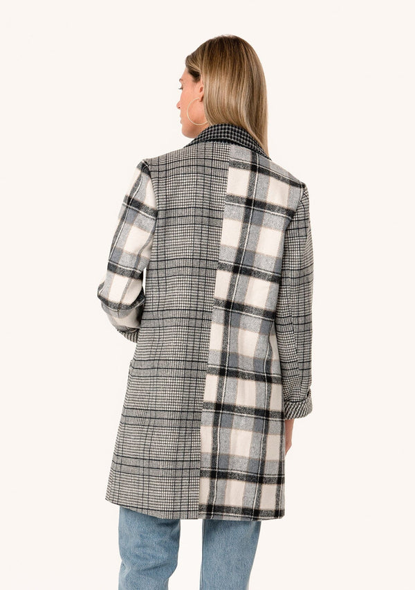 [Color: Taupe/Grey] A back facing image of a blonde model wearing a bohemian long blazer coat in a grey patchwork plaid. With long sleeves, a notched lapel, a button front, and patch side pockets. 