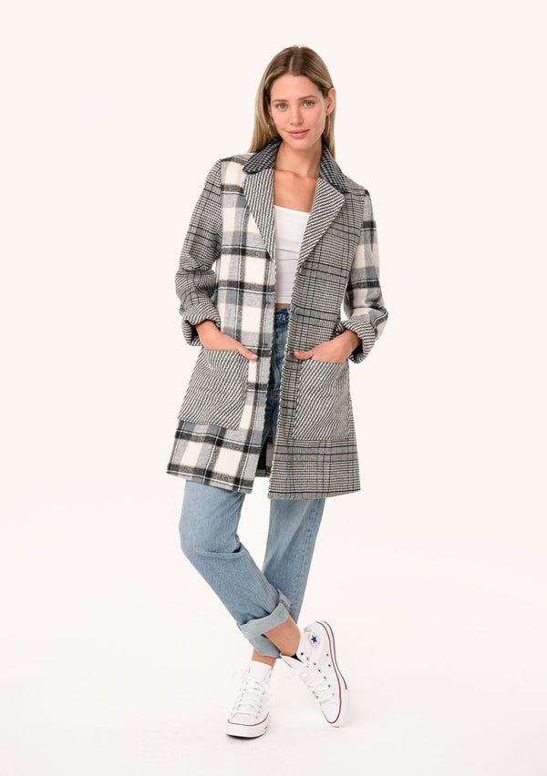 [Color: Taupe/Grey] A full body front facing image of a blonde model wearing a bohemian long blazer coat in a grey patchwork plaid. With long sleeves, a notched lapel, a button front, and patch side pockets. 