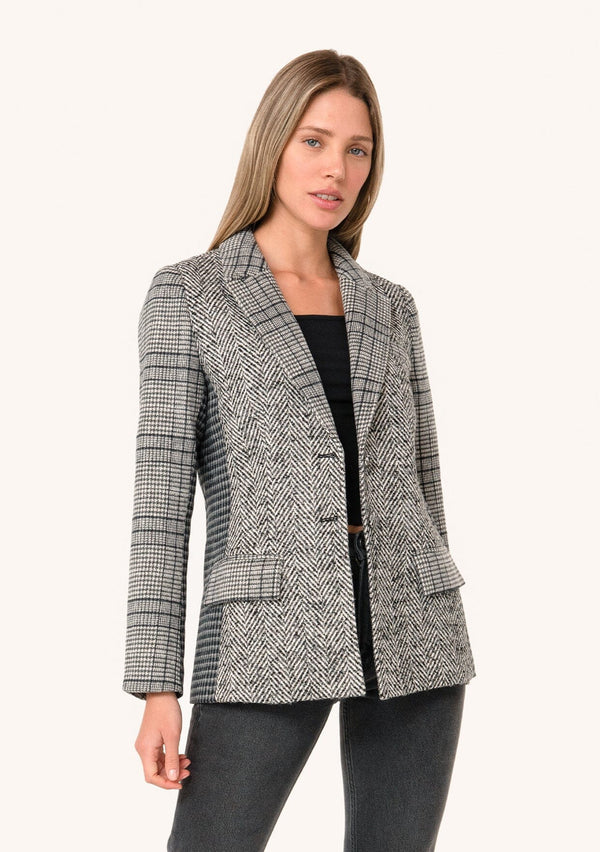 [Color: Cream/Black] A front facing image of a blonde model wearing a classic blazer in a grey patchwork plaid. With a button front, long sleeves, and side flap pockets. 