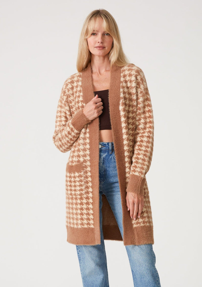 [Color: Taupe/Cream] A front facing image of a blonde model wearing a mid length fuzzy sweater coat in a brown and cream houndstooth plaid design. With long sleeves, an open front, and side patch pockets. 