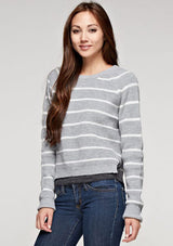 [Color: Heather Grey/Ivory] A brunette model wearing a stripe knit pullover sweater with long sleeves, a  crew neckline, and side vents. The perfect throw on for casual outings. 