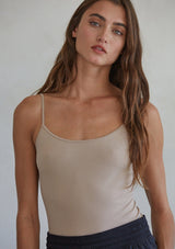[Color: Light Taupe] A front facing image of a brunette model wearing a basic taupe cami with a stretchy, seamless fit and fixed spaghetti straps. 
