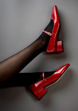 Red mary jane pumps in a classic patent leather with an adjustable strap and a square toe. 