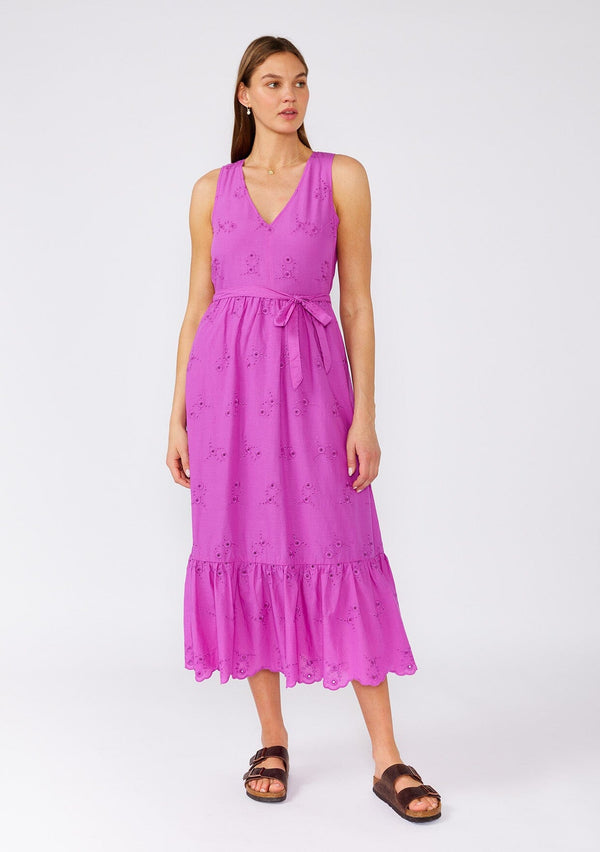 [Color: Orchid] A front facing image of a brunette model wearing a an orchid purple bohemian mid length dress made with embroidered eyelet. A sleeveless spring dress with a v neckline, a tiered skirt, an adjustable waist tie, and a back keyhole with button closure. 