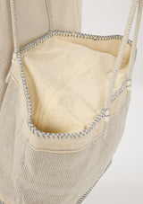 [Color: Blue/Natural] A detail image of a bohemian tote bag in a natural and light blue texture. With stitched detail throughout, two rope handles, and a top zip closure.